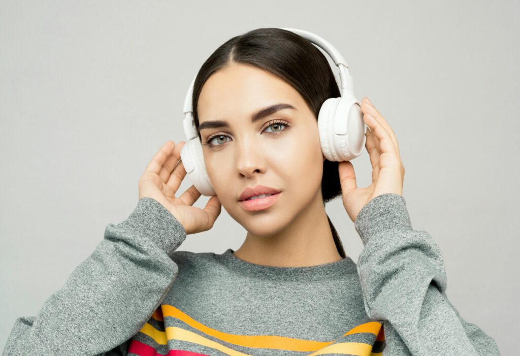 Portrait of a young woman wearing headphones, enjoying music indoors with a casual expression.