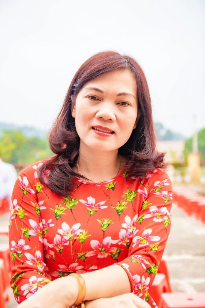 Smiling woman wearing a vibrant floral top, captured outdoors on a bright day.